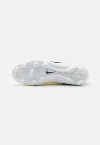 Nike focicipő talpa fehér színben, fekete akcentusokkal, apró kör alakú stoppokkal a tapadásért és ívelt, aerodinamikus kialakítással.