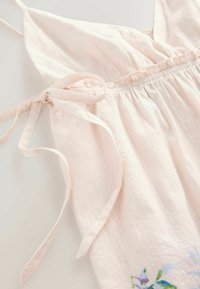 Svetlo roza lanena obleka z tankimi naramnicami in nabranim pasom. Ima detajle cvetlične vezenine na robu in zaveze na pasu.