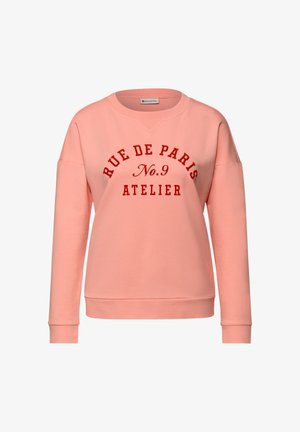 Różowa bluza z okrągłym dekoltem, o luźnym kroju, z czerwonym nadrukiem "RUE DE PARIS No.9 ATELIER." Miękki materiał.