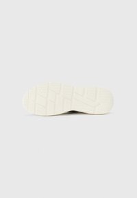 Suola delle scarpe in materiale gommoso bianco, caratterizzata da una texture con scanalature e impugnature per un migliore grip. Design piatto, punta arrotondata.