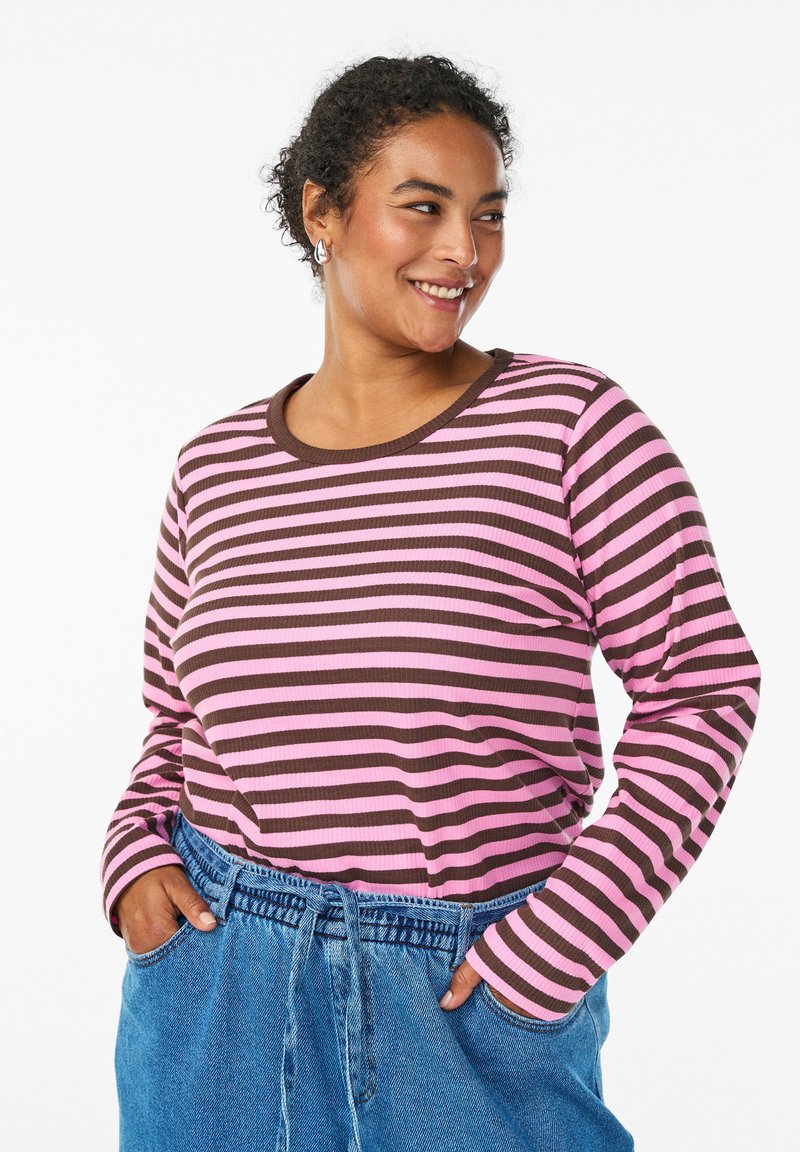 Haut rayé à manches longues en tissu côtelé rose et marron avec un col rond. Associé à un pantalon en denim bleu taille haute.