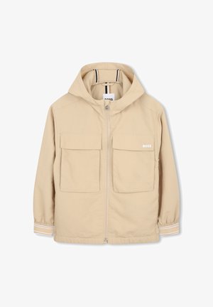 Veste à capuche beige en tissu léger, dotée de deux poches avant à rabat, d'une fermeture éclair frontale et de détails rayés sur les manches.