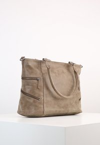 Beige mockalväsk med två dragkedjefickor fram, runda handtag och en mjuk textur. Designen är rymlig och praktisk.