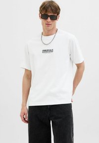 Hvid bomulds t-shirt med korte ærmer, der har et sort trykt logo "ORIGINALS SUMMER EDITION" på forsiden. Sæt sammen med sorte jeans.