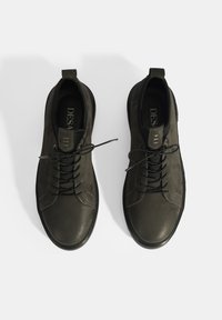 Zwarte leren sneakers met een gladde textuur, ronde neus, vetersluiting aan de voorkant en een minimalistisch ontwerp. Voorzien van een aantrekstrip en subtiele branding.