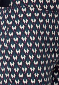 Blauwe stof met een geometrisch patroon van witte diamanten omlijnd met roze, met een gladde, gestructureerde afwerking.