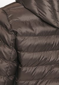 Brun vadderad jacka med quiltdesign och horisontella sömmar, slät textur och huva. Tyget verkar glansigt och lätt.