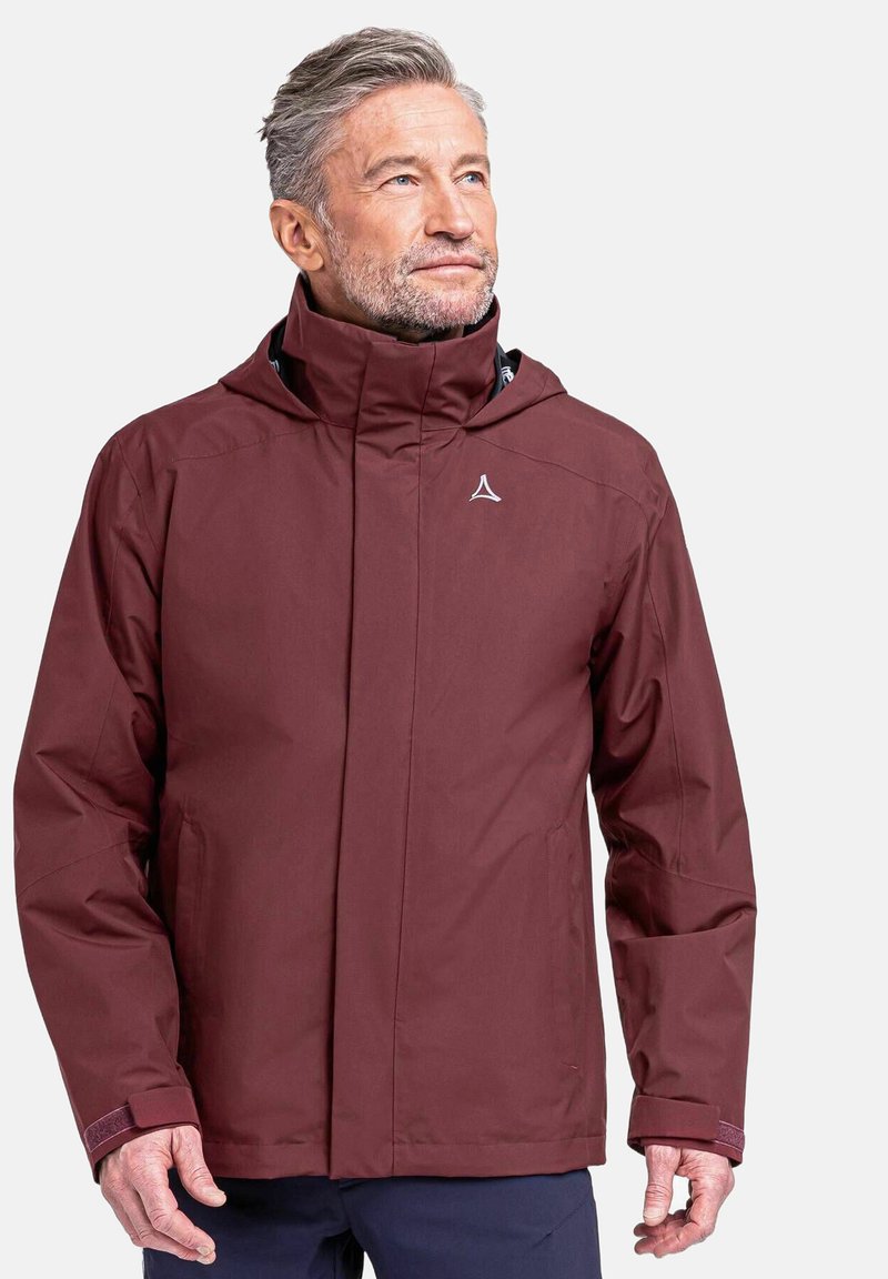 Wasserabweisende kastanienbraune Jacke mit hohem Kragen, vorderem Reißverschluss und verstellbarem Kapuze. Glatte Textur und dezentes Logo auf der Brust.