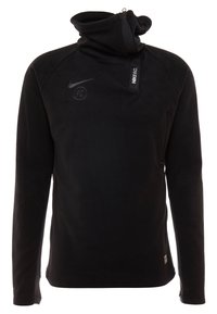 Pull-over Nike noir à manches longues avec fermeture éclair col haut, logo Nike swoosh, emblème "FC" et texte "NIKE F.C." sur la languette du col.