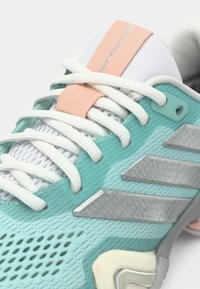 Τυρκουάζ αθλητικό παπούτσι με λευκά κορδόνια, υφασμένο επάνω μέρος, ασημένιες λεπτομέρειες και ροδακινί ετικέτα. Διαθέτει σχεδιασμό με μοτίβο και στιβαρή σόλα.