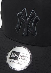 Casquette de baseball noire avec un logo NY brodé dans une teinte plus foncée. Elle présente un tissu texturé, une visière courbée et une sangle réglable.