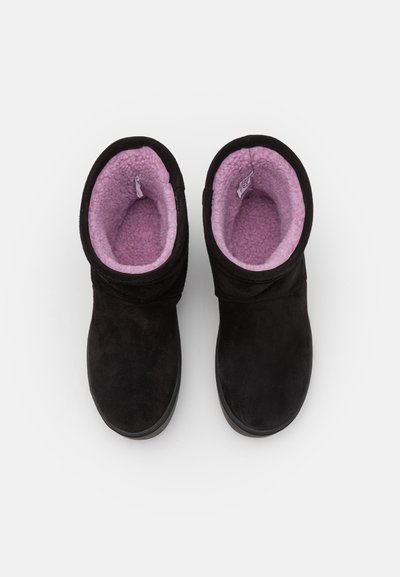 Botines de ante negro con un suave forro de forro polar rosa, con puntera redondeada y un diseño holgado. Sin herrajes ni patrones visibles.