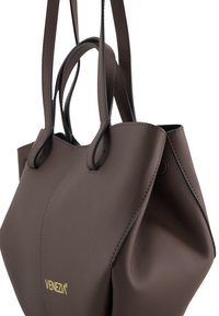 Brown leather tote bag with a minimalist design. Features dual handles, contrasting stitching, and a logo on the front. Soft texture, no visible hardware.