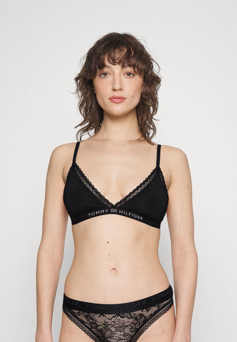 Crni čipkasti bralette s trokutastim šalicama, podesivim naramenicama i oznakom branda. Uparen s matching crnim čipkastim gaćicama s cvjetnim uzorcima.