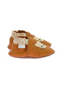 Petits chaussons en cuir marron pour bébé avec un design de visage de chat, un liseré élastique doré à la cheville et une semelle douce. Présente une étiquette de marque bleue sur le côté.