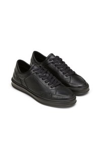 Schwarze Ledersneaker mit glatter Textur, abgerundetem Zehenbereich und dicker Sohle. Verfügt über schwarze Schnürsenkel und dezente Perforationen an der Seite.