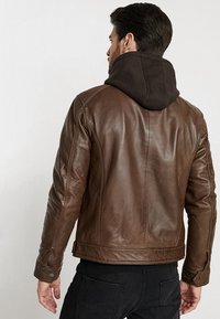Bruine leren jas met een zwarte capuchon, slim fit ontwerp, subtiele stikdetails en drukknopen. Casual stijl.