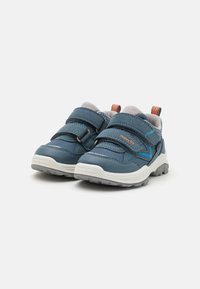 Blaue Sportschuhe mit grauen Mesh-Details, doppelten Klettverschlüssen, strukturierten Sohlen und orangefarbenen sowie türkisfarbenen Akzenten an der Seite.