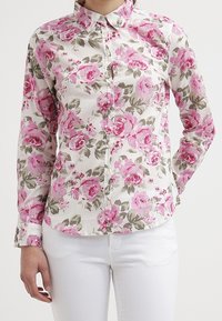 Blomstrig skjorta med knappar som har en vit bakgrund med rosa rosor och gröna blad, långa ärmar och en klassisk krage.