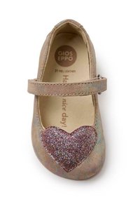 Zapato Mary Jane de cuero en marrón claro, con un acento de corazón brillante en rosa. Cuenta con una tira en el empeine y una puntera redondeada.