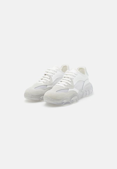 White sneakers made of leather and suede with a mesh panel, featuring a transparent air-cushioned sole and six eyelets for laces.