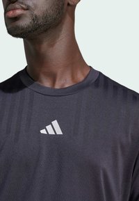 Black athletic t-shirt featuring vertical striped textures, a crew neck, and a reflective white logo on the chest.