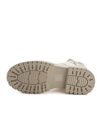 Soletta di stivaletto beige chiaro con profonde scanalature e design antiscivolo, caratterizzata da una punta rotonda e dettagli di imbottitura lungo i lati.