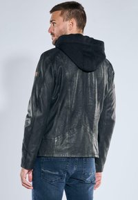 Black leather jacket with a textured finish, featuring a black hood, fitted silhouette, and visible seam detailing. Back view shown.