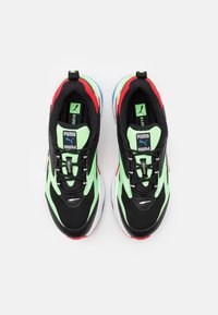 Baskets en mesh noires avec des accents verts et rouges, dotées d'une épaisse semelle blanche, d'un branding marqué et d'une surface texturée pour une meilleure adhérence.