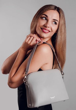 Gray leather handbag with a rounded top, silver hardware, and an adjustable strap. Features a simple, smooth texture and brand logo on the front.