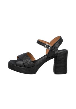 Sandalía de tacón alto de cuero negro con tacón grueso, correa en el tobillo con hebilla plateada y tiras delanteras cruzadas.