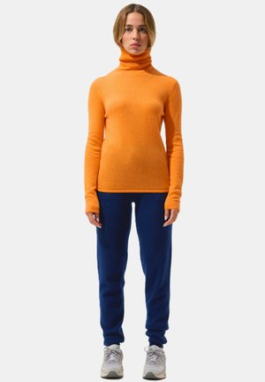 Maglione a collo alto arancione in morbido tessuto a maglia, abbinato a pantaloni jogger blu navy. Vestibilità comoda con maniche lunghe e polsini a costine.