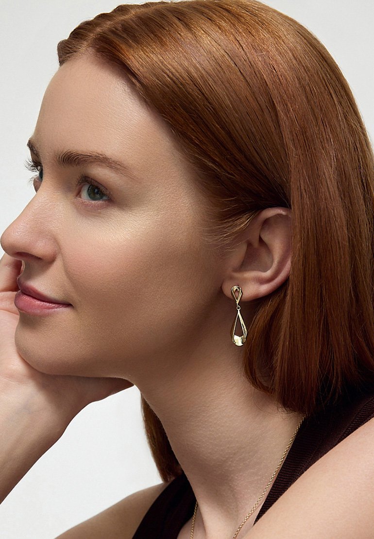 Złote kolczyki w kształcie łzy z pętelką na górze. Gładka, błyszcząca powierzchnia z wypolerowanym wykończeniem.