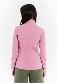 Svetlo ružová košeľa s dlhým rukávom a vysokým golierom, hladká textúra a diskrétne logo. Navrhnutá pre pohodlie s priliehavým strihom.