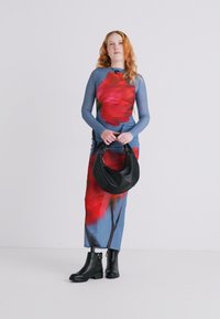Robe à manches longues avec un motif floral bleu et rouge, associée à un sac à main noir et des bottines. Tissu lisse avec une conception ajustée.