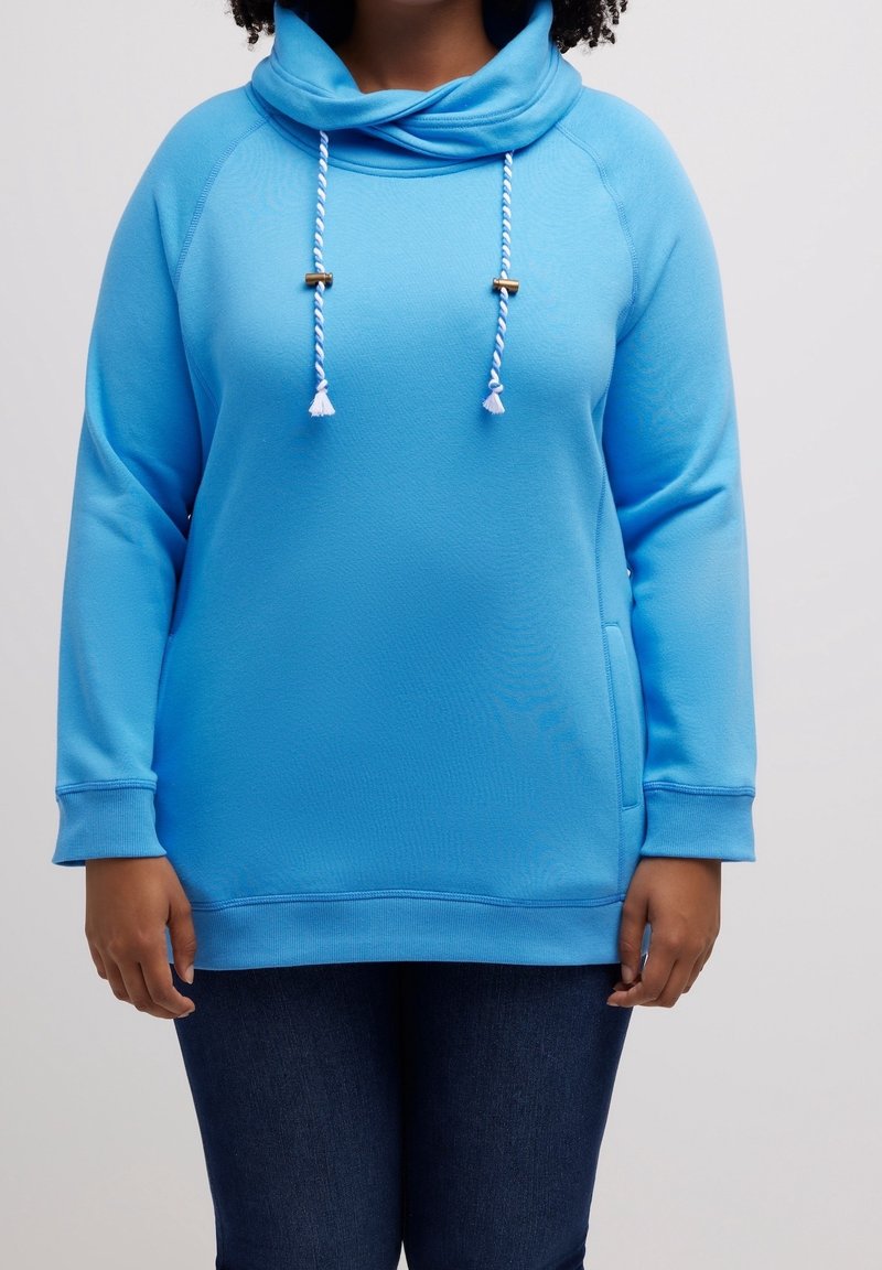 Sudadera azul con cuello cruzado, cordones con borlas y acabado texturizado. Mangas largas y un bolsillo delantero. Corte informal.