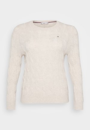 Cable-knit cream sweater with a round neckline, long sleeves, and ribbed cuffs. Features a small logo on the chest. Made from soft material.