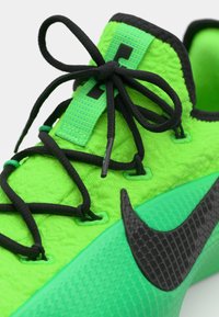 Basket vert vif avec un matériau texturé, des lacets noirs et un logo Nike noir avec un motif en diamant sur la semelle.