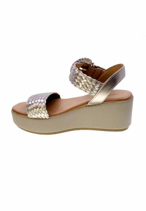 Sandalo con zeppa beige da donna con cinturini intrecciati metallici alla caviglia e alle dita, soletta marrone e suola spessa per una maggiore altezza.