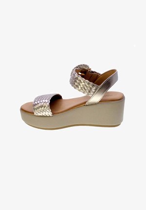 Sandalo con zeppa beige da donna con cinturini intrecciati metallici alla caviglia e alle dita, soletta marrone e suola spessa per una maggiore altezza.
