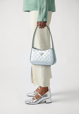 Borsa a tracolla azzurro chiaro con motivo in rilievo, dettagli in argento e forma curva. Abbinata a pantaloni beige e scarpe argento metallico.