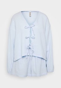 Lyseblå, cropped top i tekstureret stof med lange ærmer, bred udskæring og detalje med sløjfe foran. Giver en afslappet pasform.