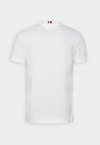 T-shirt bianco a maniche corte con colletto classico, texture morbida e una striscia a righe blu navy, rossa e bianca nella parte posteriore del collo.