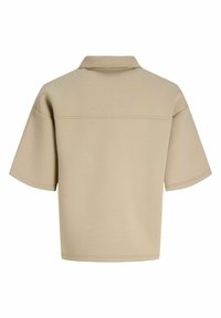 Polo beige à manches courtes, coupe large, avec une couture horizontale traversant le haut du dos.