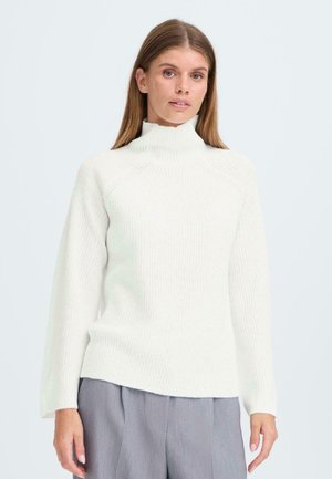 White knitted sweater with a high neck, ribbed texture, and relaxed sleeves. It features a straight hem and is paired with gray trousers.