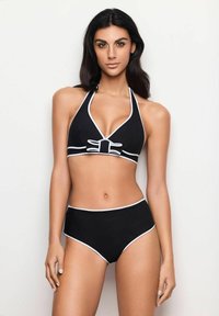 Černé bikiny s halter krkem, zdobené bílým lemem a detailem mašle, doplněné vysokými kalhotkami s bílými okraji.