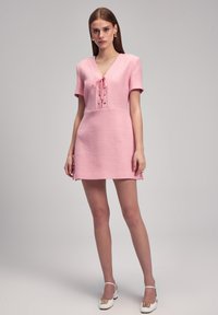 Kurzes pinkes Kleid aus strukturiertem Stoff, mit V-Ausschnitt, kurzen Ärmeln, schnürbarem Vorderteil mit Bändern und seitlichen Schlitzen.