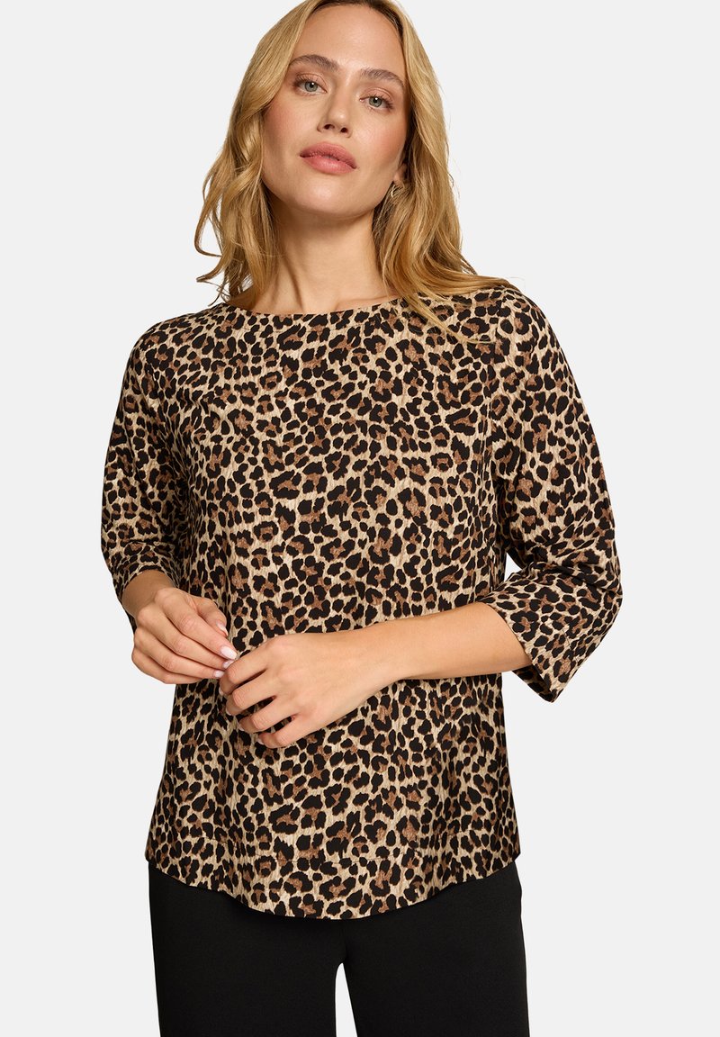 Bluse mit Leopardenmuster, drei Viertel langen Ärmeln, rundem Ausschnitt und lockerer Passform. Weicher Stoff mit strukturiertem Muster, kombiniert mit schwarzen Hosen.