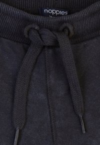 Ciemnoszare dresy z ryflowym pasem, z plecionym sznurkiem do regulacji i metką z marką "noppies". Gładka struktura.