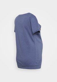 Camiseta de manga curta e decote redondo em um suave material de algodão azul. Apresenta um corte solto com uma barra ligeiramente curva e mangas enroladas.